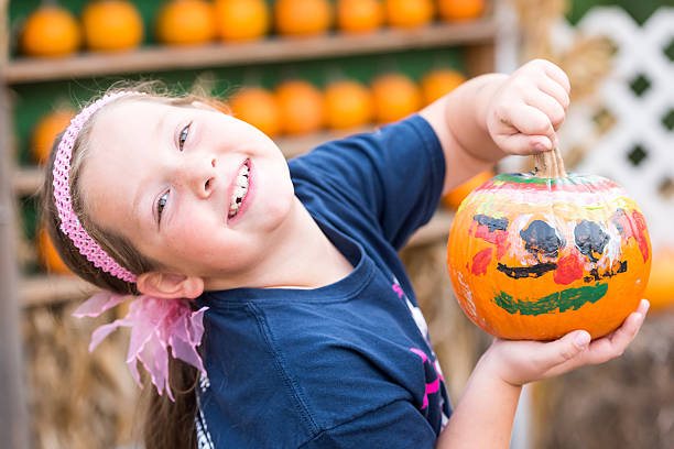 Smiling caucasian  little girl showing her painted pumpkin